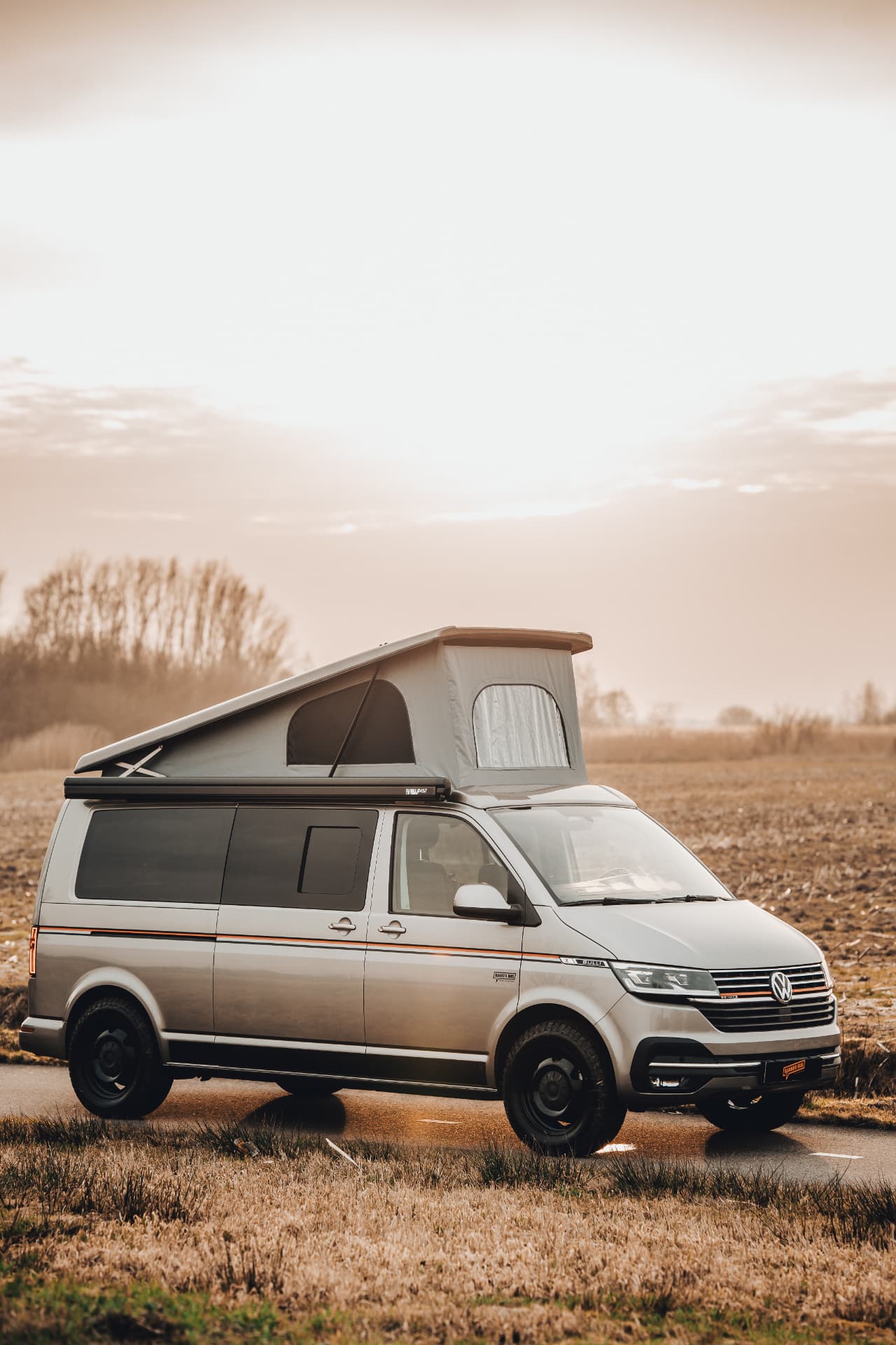 Camper met opklapbare daktent op een landelijke weg
