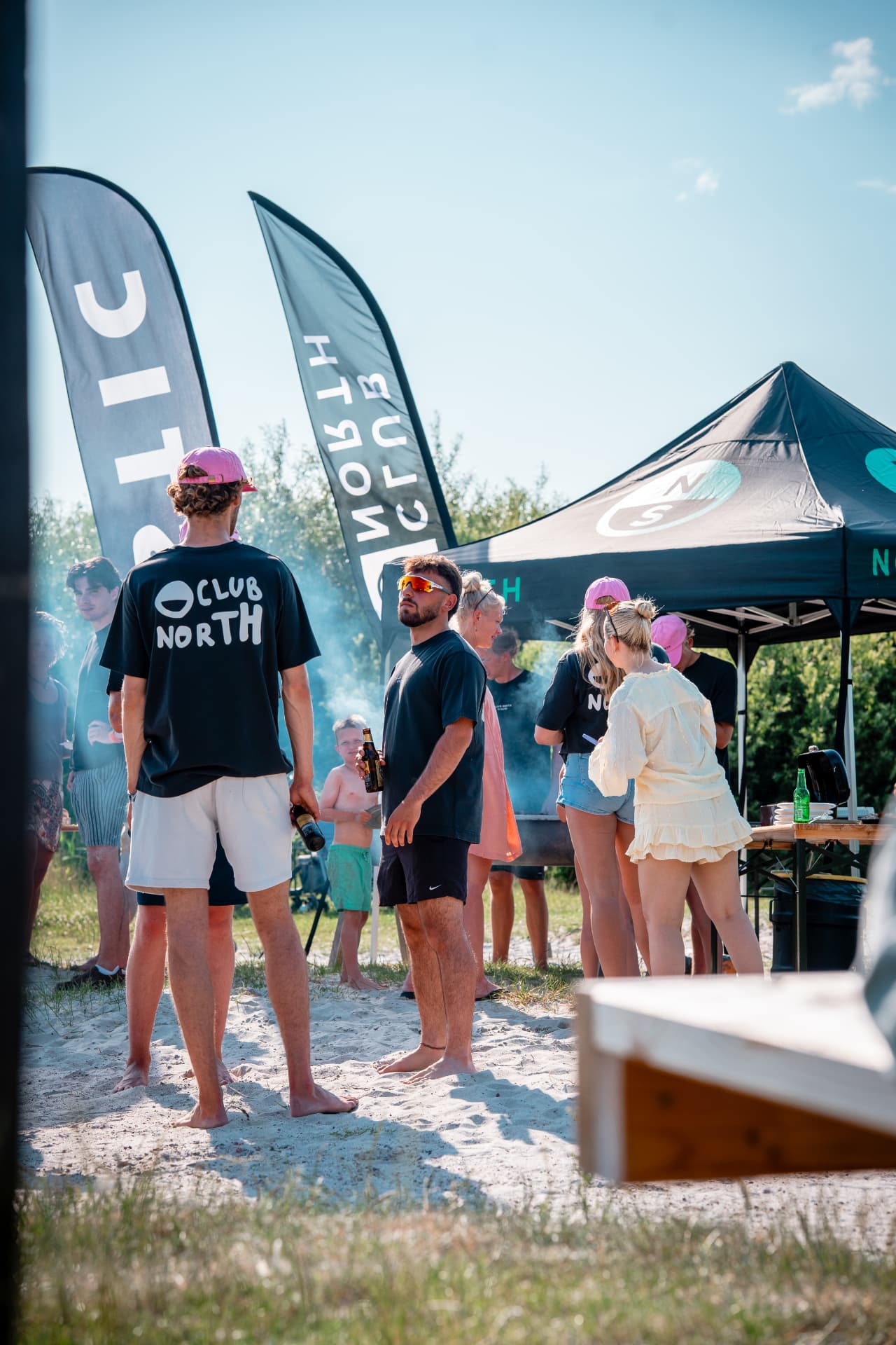 Mensen in Club North-shirts bij een strand-BBQ