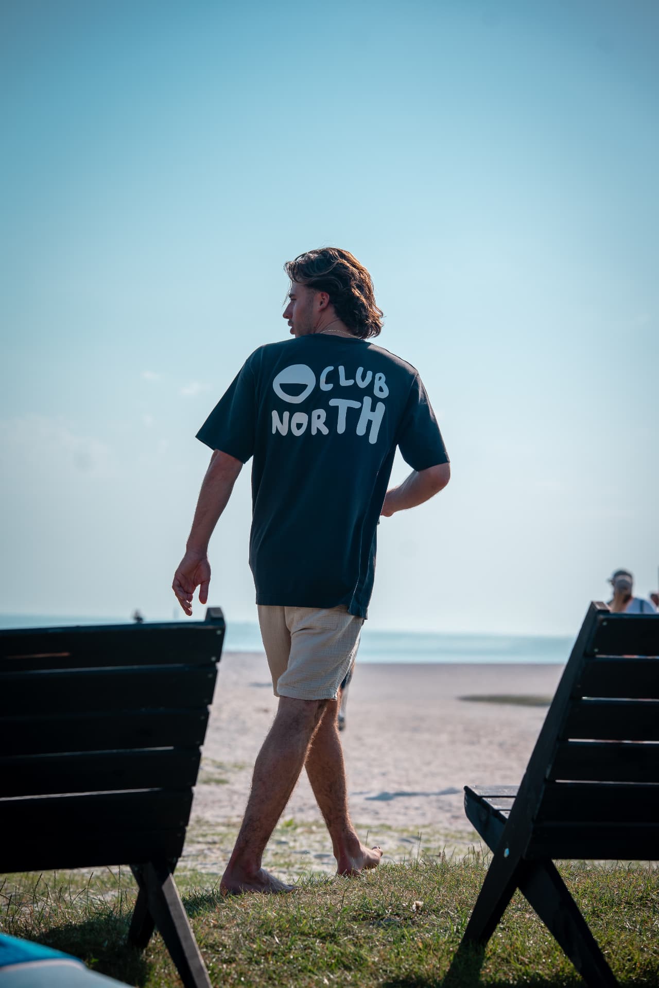 Man in een Club North-shirt loopt over het strand
